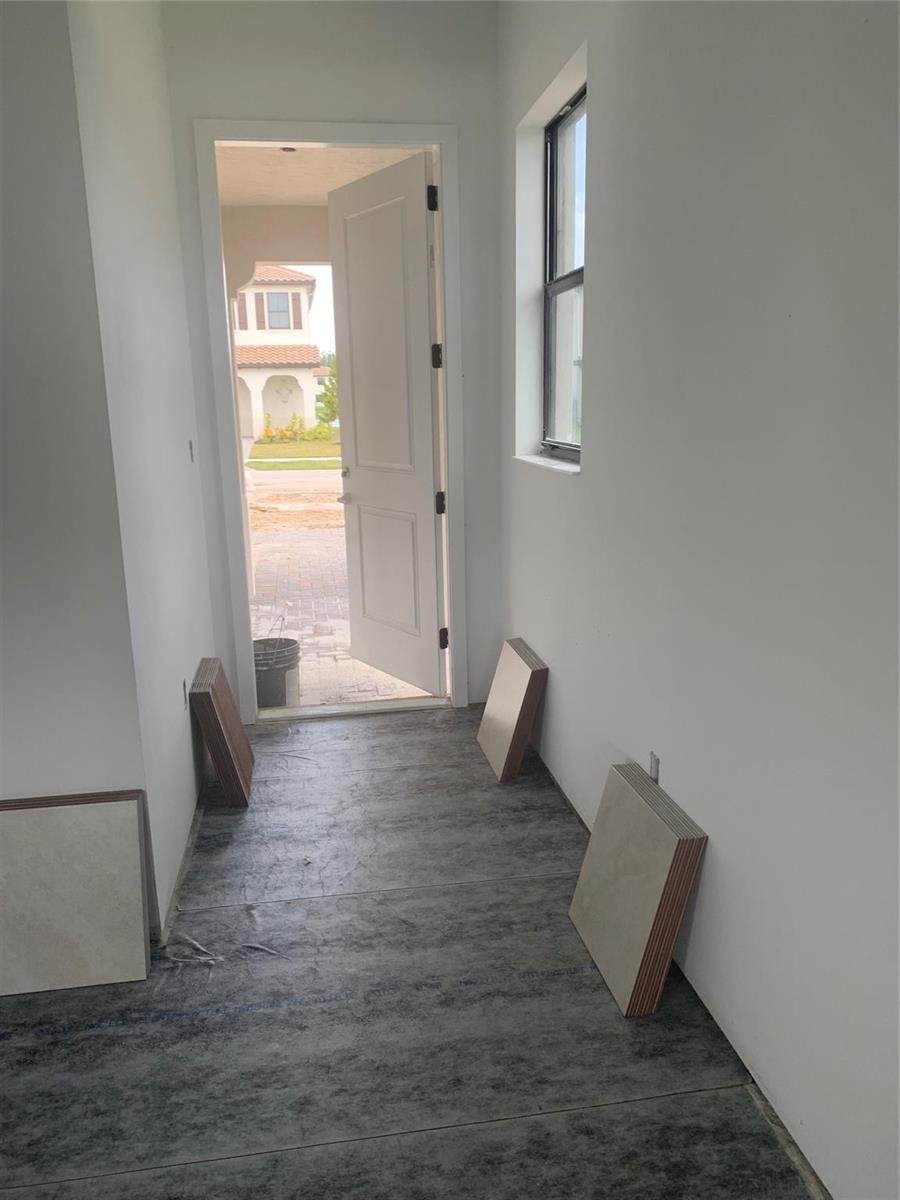 An unfinished entryway features gray flooring underlayment, white walls, and a door opening to outside — 5637 W Cerva Lane, Ave Maria FL 34142, AVE MARIA, FL