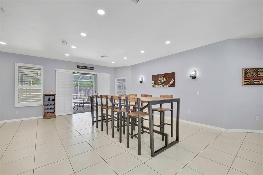 A spacious dining room features tile flooring, recessed lighting, and a large metal-framed table — 14105 MARLBERRY WAY, ODESSA, FL