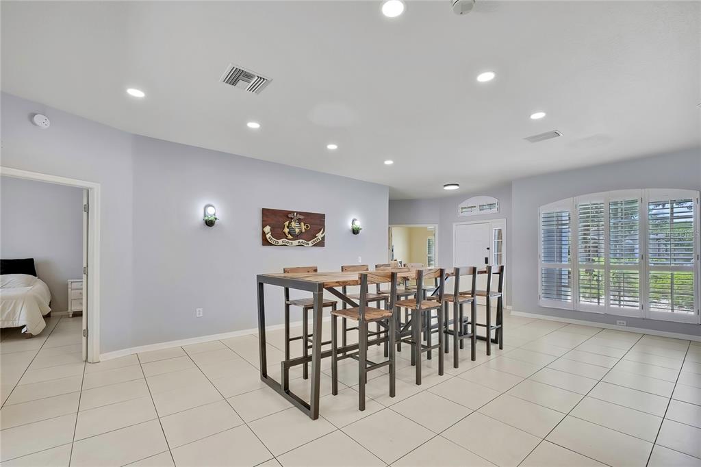 A dining room features a long wooden table with metal stools and light tile flooring — 14105 MARLBERRY WAY, ODESSA, FL