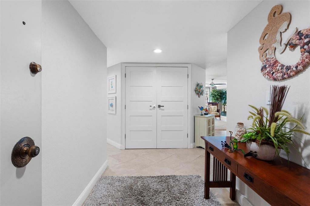 A bright entryway features tile flooring, a wooden console table, and white double doors — 1430 GULF BOULEVARD UNIT 406, CLEARWATER BEACH, FL