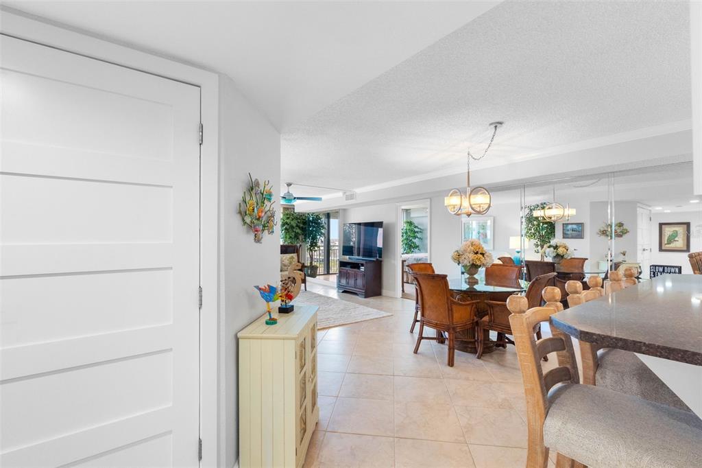 An open-concept living and dining area features tile flooring, a breakfast bar, and balcony views — 1430 GULF BOULEVARD UNIT 406, CLEARWATER BEACH, FL