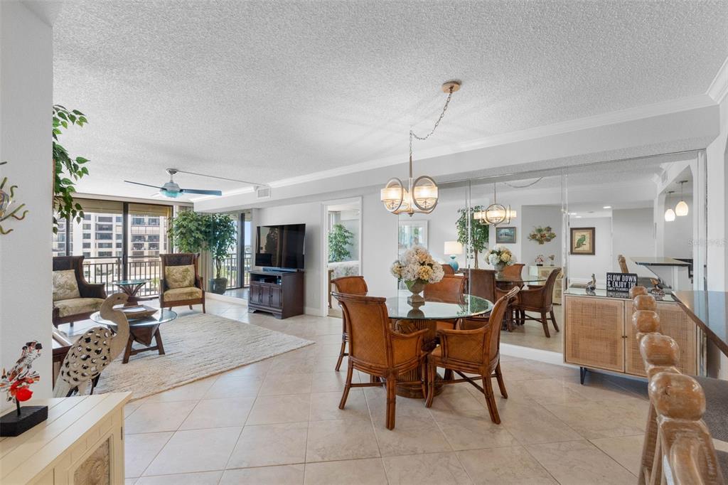 A bright living and dining area features tile floors, wicker furniture, and a mirrored wall — 1430 GULF BOULEVARD UNIT 406, CLEARWATER BEACH, FL