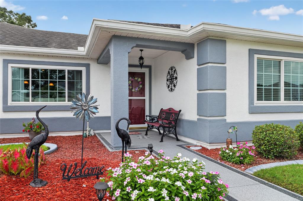 The exterior of a house features a covered entryway, a bench, and decorative lawn ornaments — 13600 SE 87TH CIRCLE, SUMMERFIELD, FL
