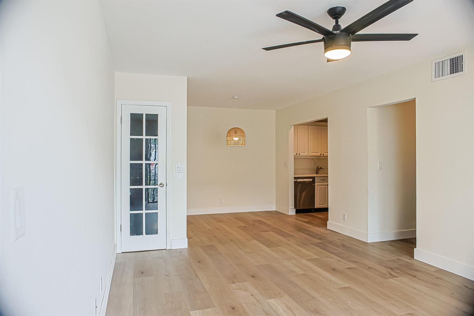 An interior view of a room with light wood flooring, a ceiling fan, and kitchen — 130 Cypress Club Drive # 309, Pompano Beach FL 33060, POMPANO BEACH, FL