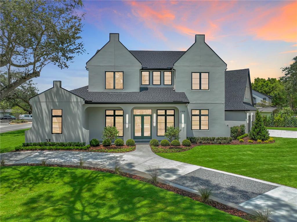 A two-story house with a light gray stucco exterior, dark roof, and arched entryway — 2905 PARKLAND DRIVE, WINTER PARK, FL