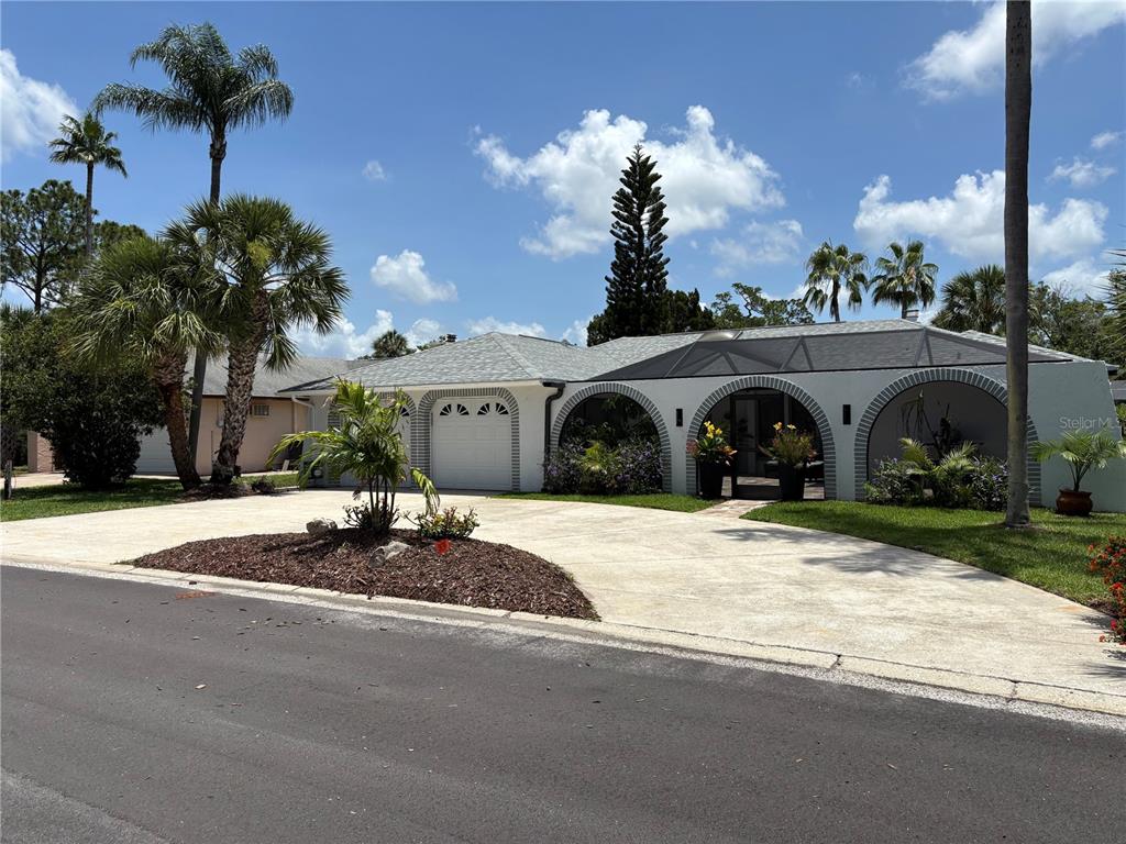 A single-story house with a white stucco facade, arched entryways, and a paved driveway — 5514 GRIDLEY LANE, NEW PORT RICHEY, FL