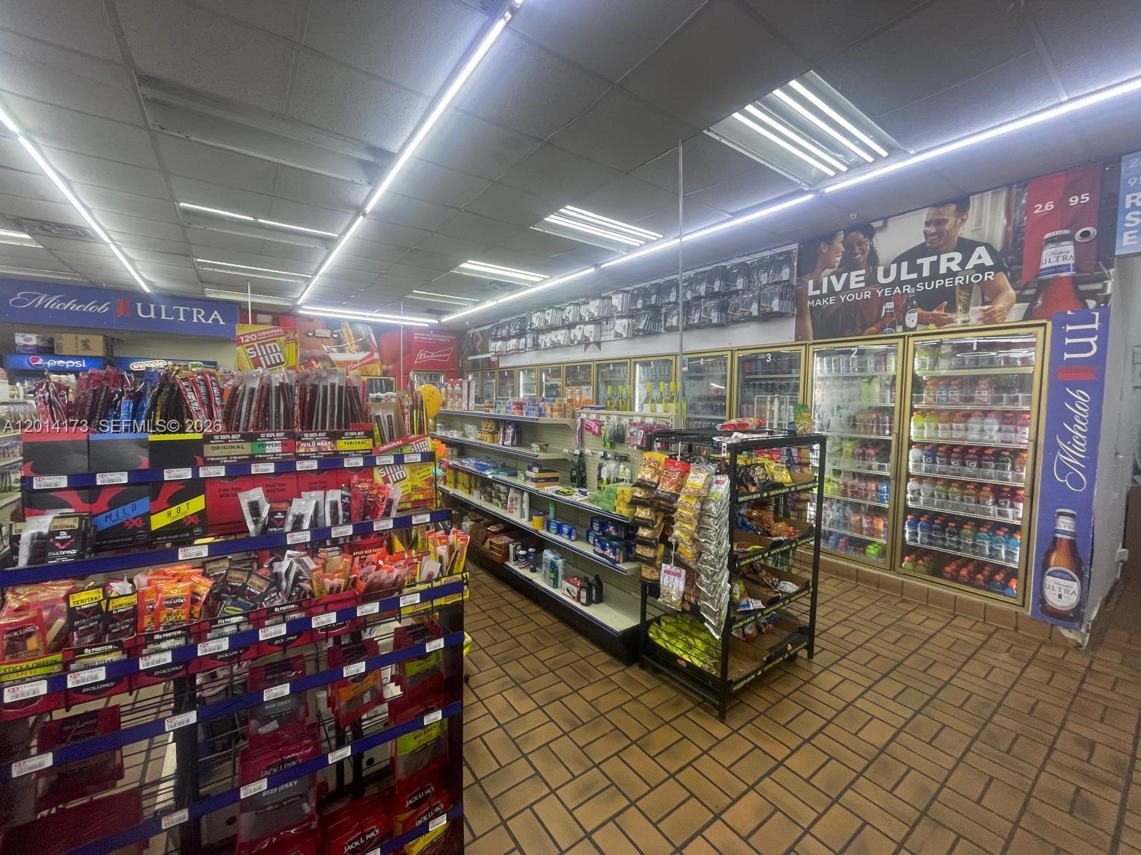 A convenience store interior features rows of snack displays and glass-fronted beverage refrigerators — 895 N Nova, Daytona FL 32117, DAYTONA, FL