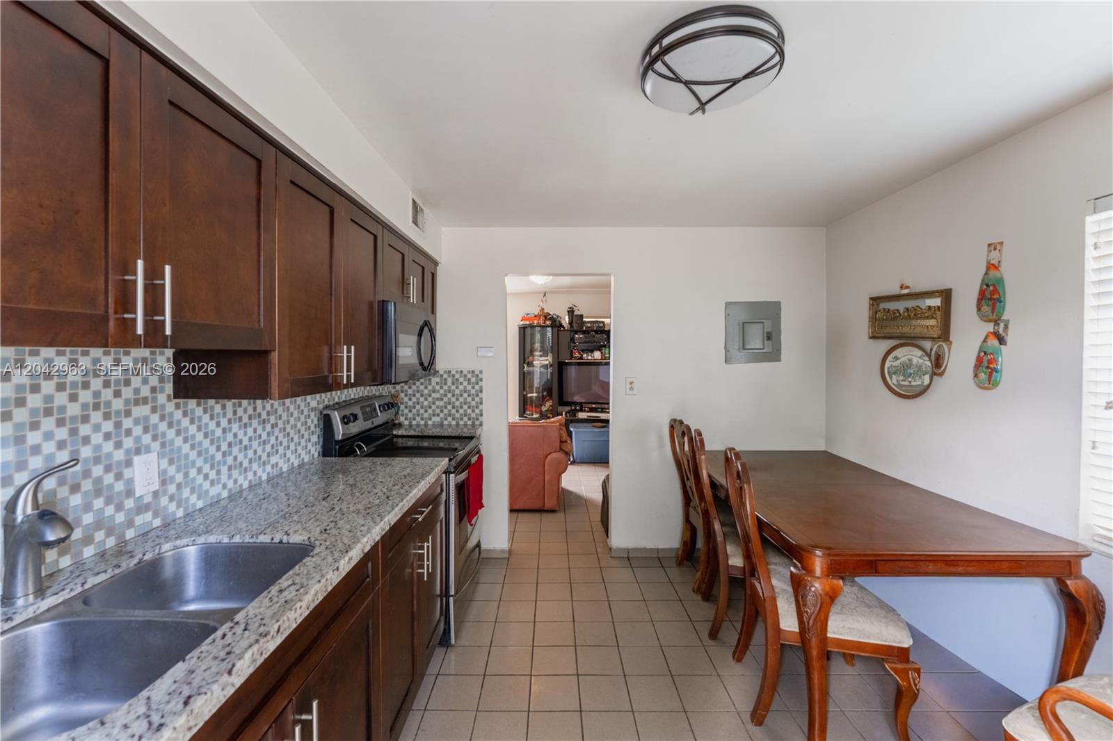 A kitchen with dark wood cabinets, granite countertops, and a dining table with chairs — 9265 SW 38th St, Miami FL 33165, MIAMI, FL
