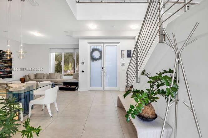 A bright, modern entryway features a glass staircase, tile floors, and a view into the living room — 10250 NW 75th Ter, Doral FL 33178, DORAL, FL