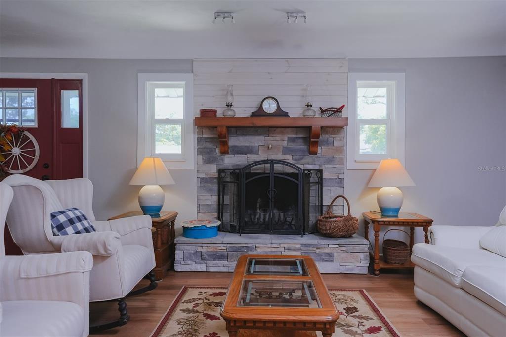 A living room features a stone fireplace with a wooden mantel and white shiplap above — 3124 S POLK AVENUE, LAKELAND, FL