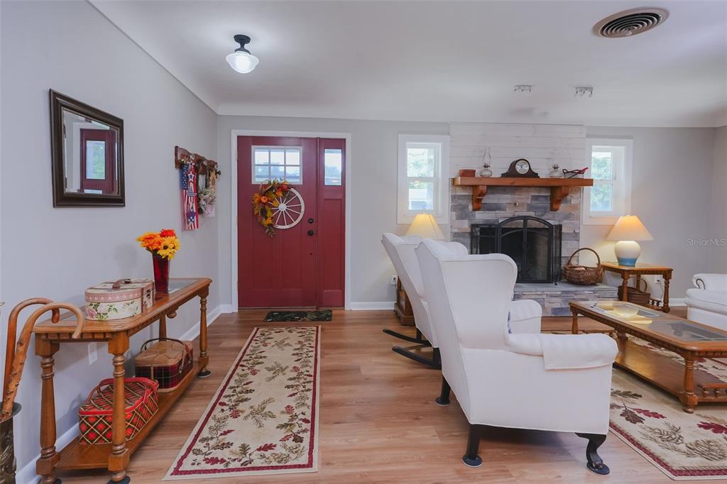 A living room features a red front door, a stone fireplace, and white wingback chairs — 3124 S POLK AVENUE, LAKELAND, FL