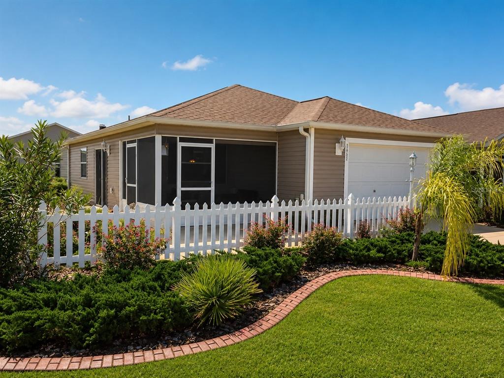 A tan house with a screened-in porch, white picket fence, and landscaped front yard — 3463 PLACIDA TERRACE, THE VILLAGES, FL