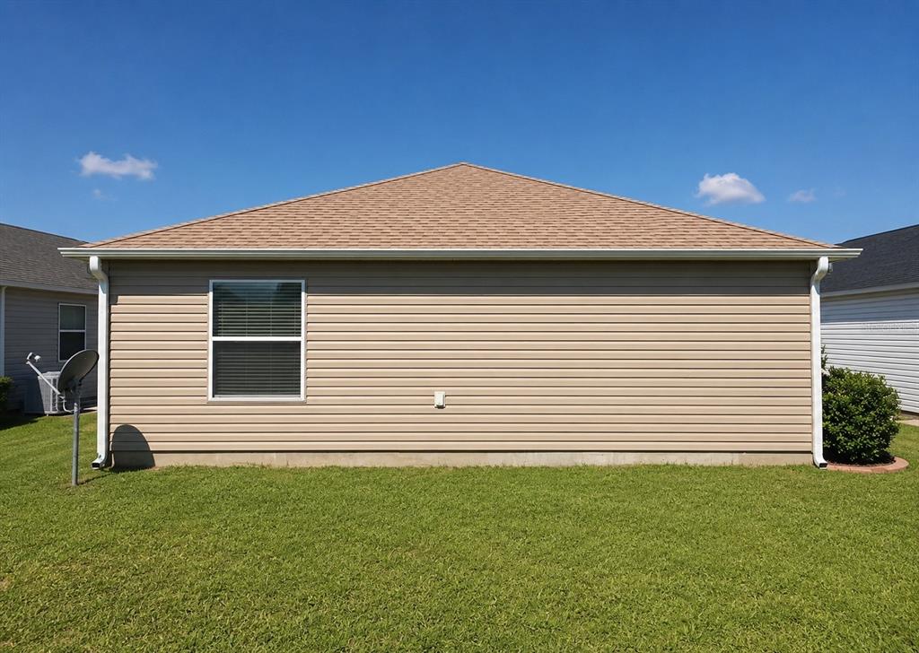 The exterior view shows the tan vinyl-sided back wall of a house with one window — 3463 PLACIDA TERRACE, THE VILLAGES, FL