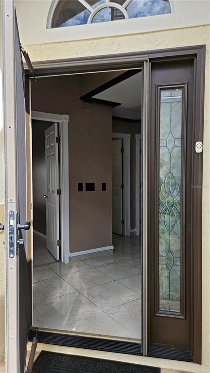 An open front door reveals a tiled entryway with interior doors and a decorative sidelight — 6053 GENTLE BEN CIRCLE, WESLEY CHAPEL, FL