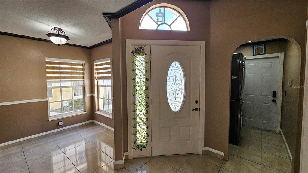 An entryway features a white front door with a sidelight, tile flooring, and arched doorway — 6053 GENTLE BEN CIRCLE, WESLEY CHAPEL, FL