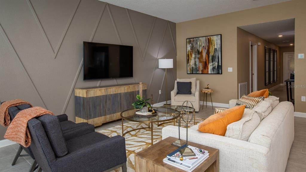 A living room features a television on a paneled wall, a sofa, and two armchairs — 5240 WORCHESTER DRIVE, KISSIMMEE, FL