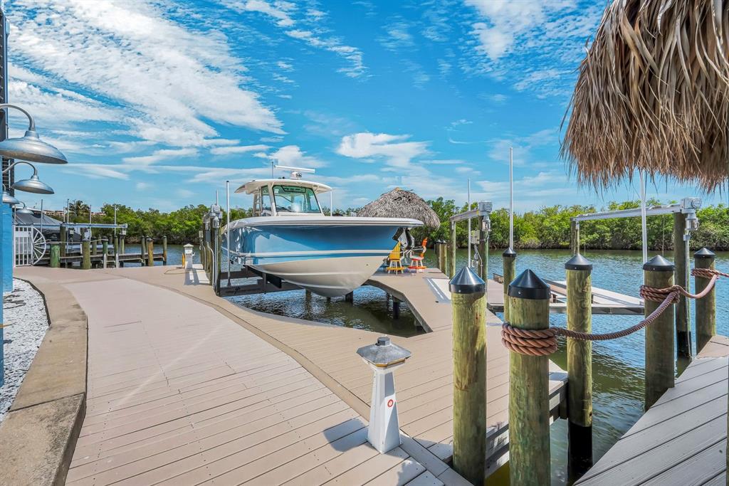 A modern kitchen with a blue island and gray cabinets overlooks a living area and water — 5826 SHELL COVE DRIVE, CAPE CORAL, FL