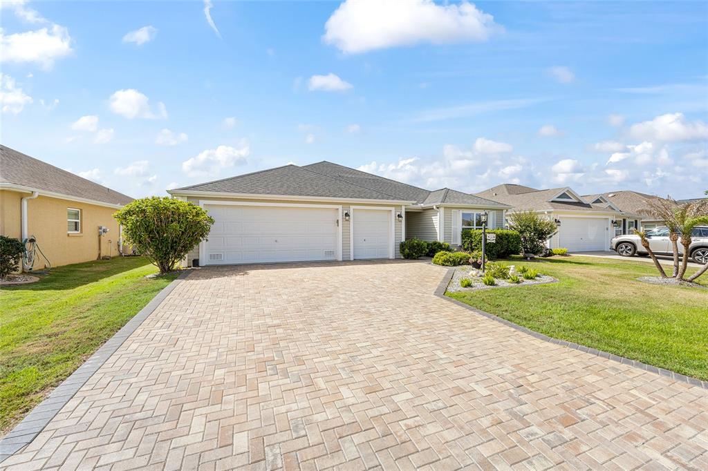 A single-story house with a paved driveway, a three-car garage, and a landscaped front yard — 475 ISLAND HOUSE PATH, THE VILLAGES, FL