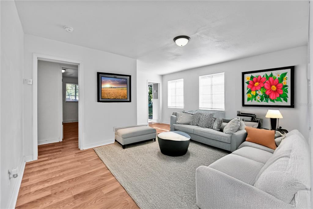 A living room with white walls, wood-look flooring, a gray sectional sofa, and two framed artworks — 1730 N ORANGE STREET, MOUNT DORA, FL