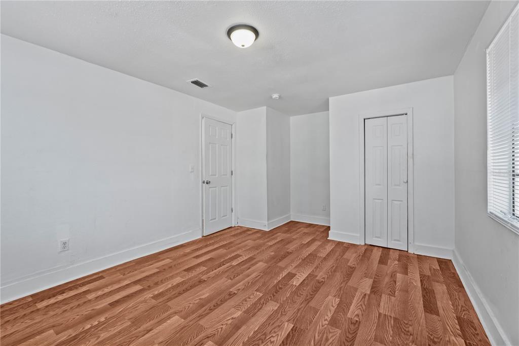 An empty bedroom features white walls, wood-look flooring, a ceiling light, and two white doors — 1730 N ORANGE STREET, MOUNT DORA, FL