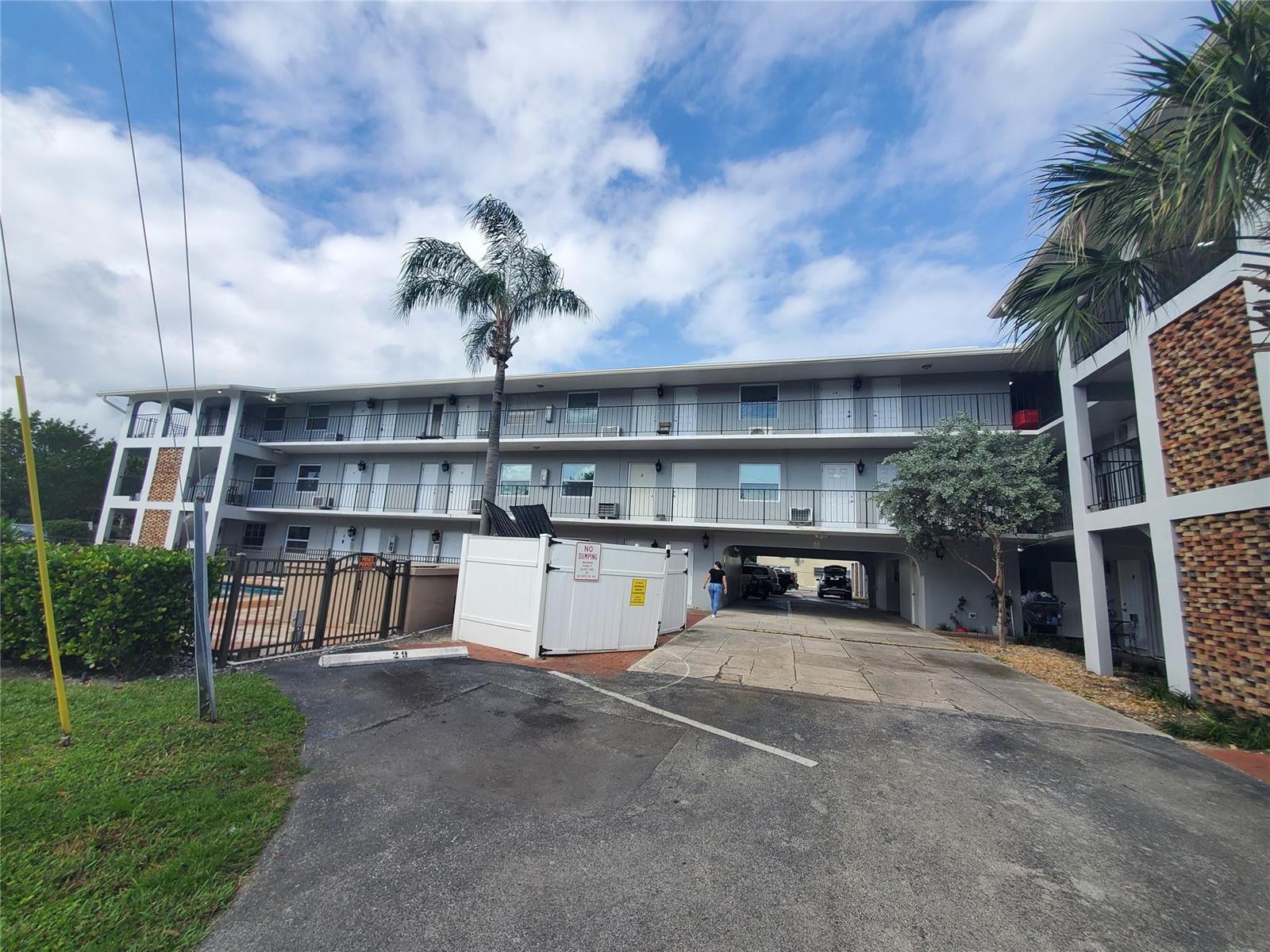A three-story apartment building with exterior walkways, a palm tree, and a covered parking area — 1021 NE 24th Avenue # 4, Pompano Beach FL 33062, POMPANO BEACH, FL