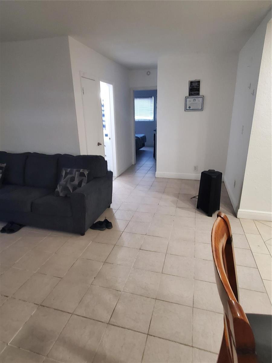 A living room with tile flooring, a dark sofa, and a doorway leading to another room — 1021 NE 24th Avenue # 4, Pompano Beach FL 33062, POMPANO BEACH, FL