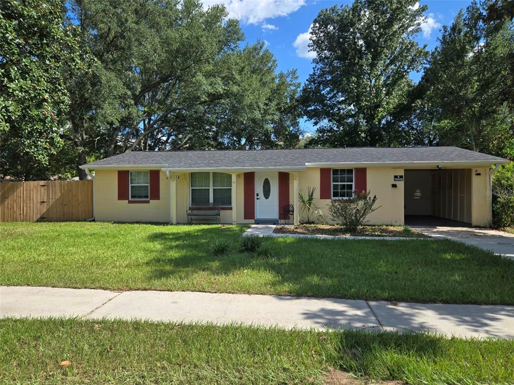 A single-story yellow house with red shutters and an attached carport sits behind a lawn — 3762 SW 147TH STREET, OCALA, FL