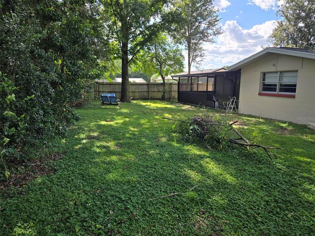 A backyard with a grassy lawn, a wooden fence, a tree, and a screened-in porch — 3762 SW 147TH STREET, OCALA, FL