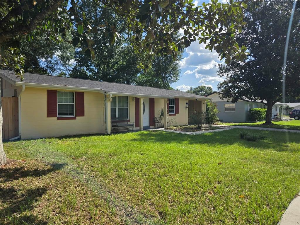 A single-story yellow house with red shutters and a covered front porch sits on grass — 3762 SW 147TH STREET, OCALA, FL