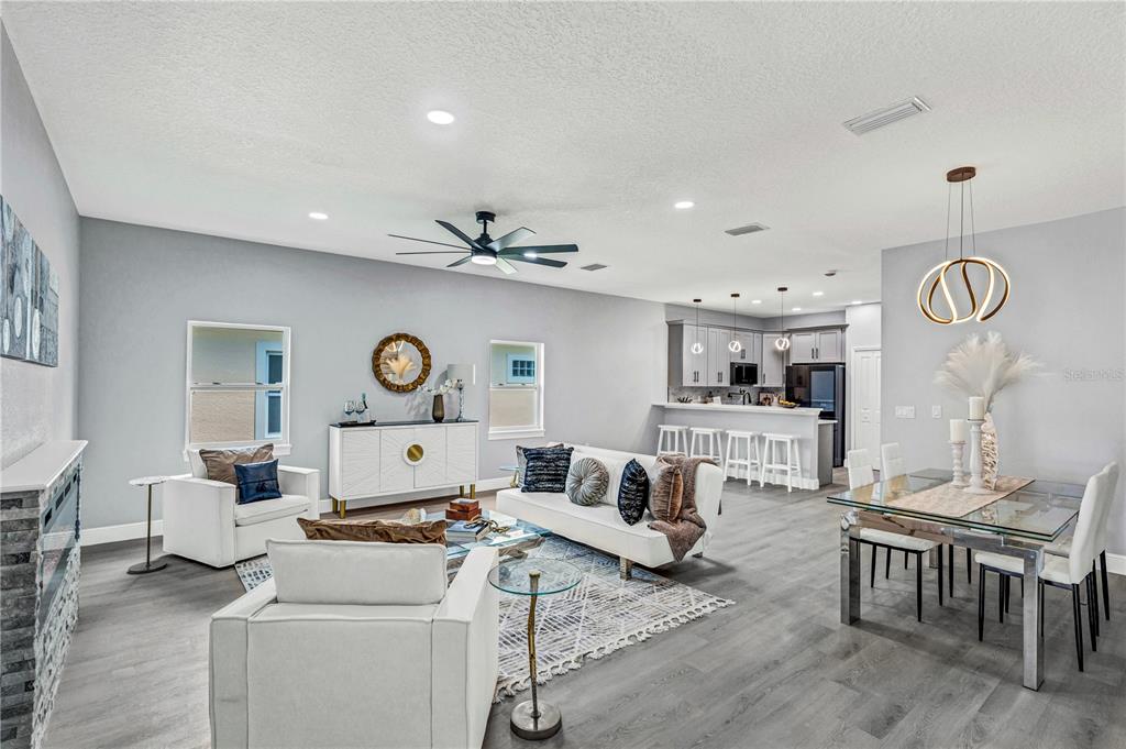 A bright open-concept living and dining area features gray wood-look flooring and modern furnishings — 721 INDIANA STREET, DAYTONA BEACH, FL