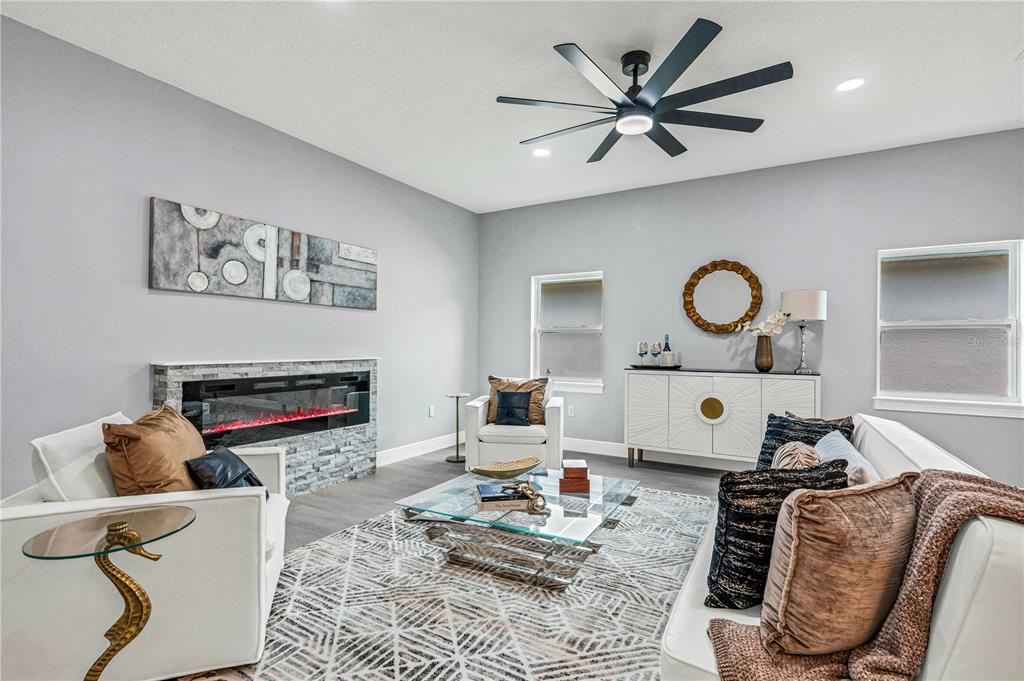 A living room features a fireplace, white armchairs, a sofa, and a modern ceiling fan — 721 INDIANA STREET, DAYTONA BEACH, FL