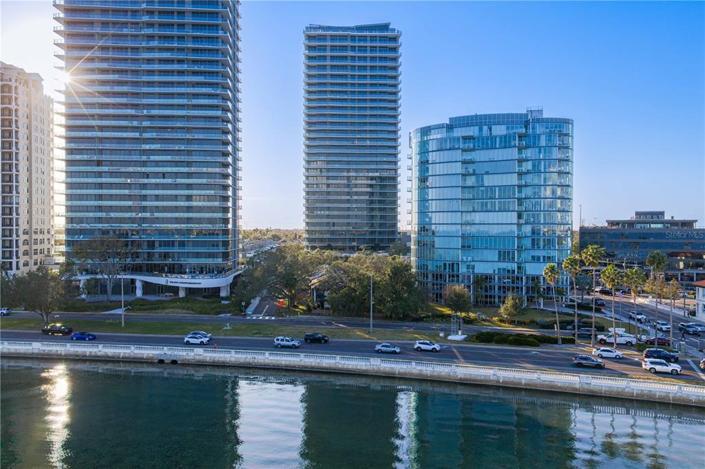 An aerial view shows three modern high-rise buildings situated along a waterfront road — 3015 S YSABELLA AVENUE UNIT 1601, TAMPA, FL