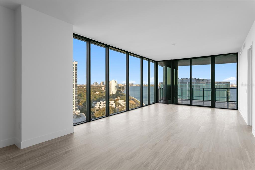 An empty room with light wood-look flooring and floor-to-ceiling windows overlooking a city and water — 3015 S YSABELLA AVENUE UNIT 1601, TAMPA, FL