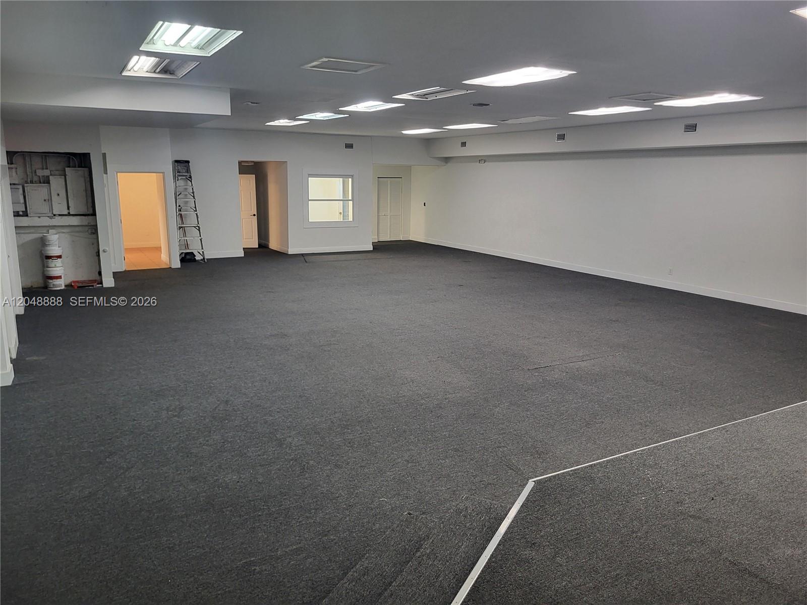 A large, open office space features gray carpeting, white walls, and multiple recessed ceiling lights — 2223 NW 26th Ave, Miami FL 33142, MIAMI, FL