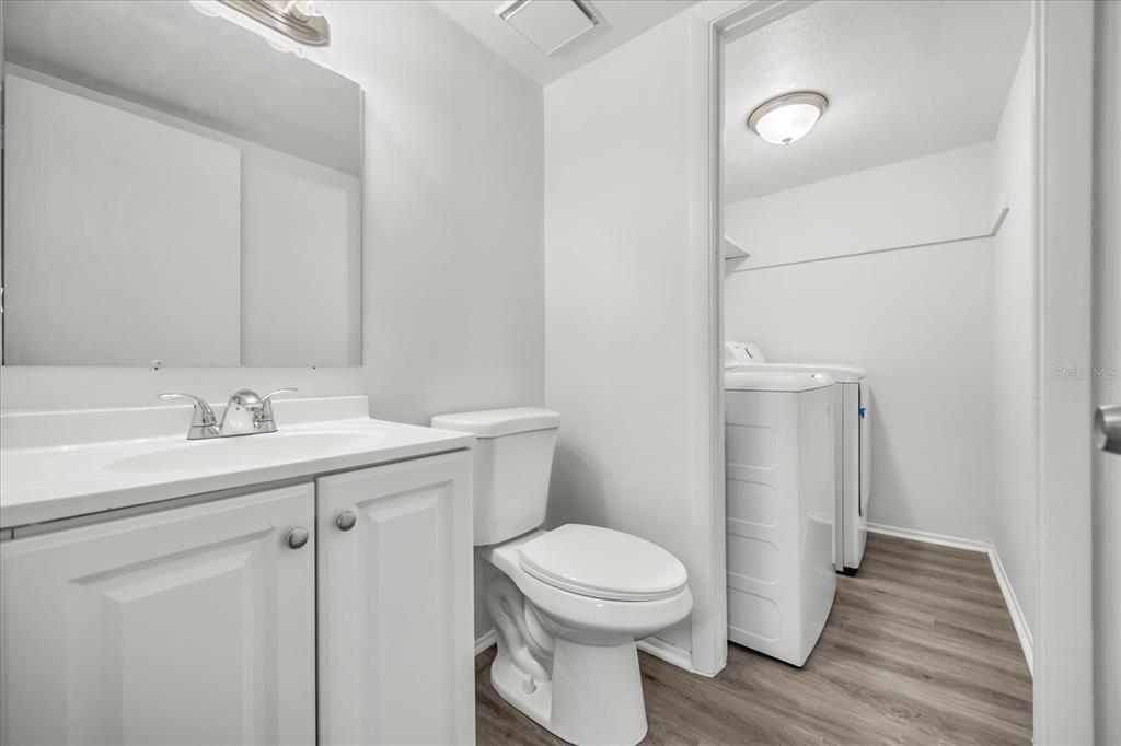 A bathroom with a white vanity, toilet, and an adjacent laundry area with appliances — 217 DEBORA COURT, ALTAMONTE SPRINGS, FL