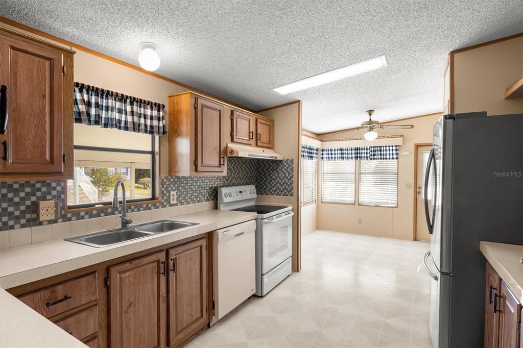 A kitchen with wood cabinets, a white stove, a dishwasher, and a double sink — 347 EDGEWOOD BOULEVARD, LAKE WALES, FL
