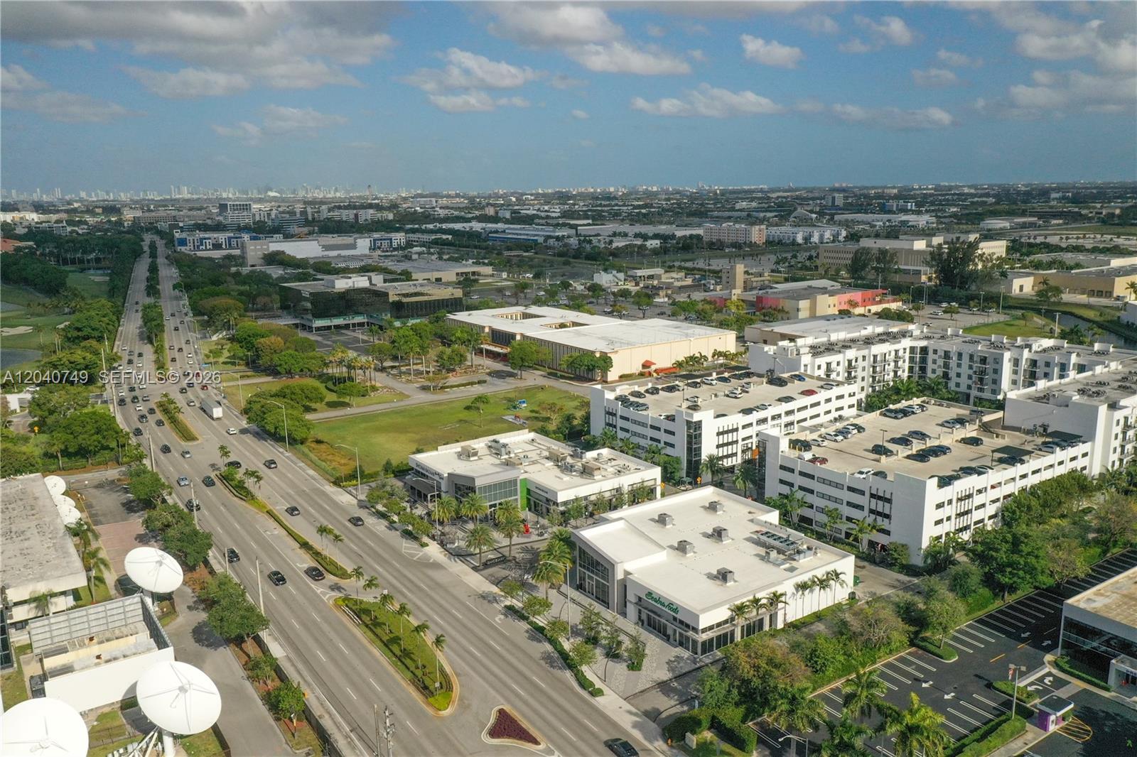 An aerial view shows a multi-lane road alongside commercial buildings, parking garages, and green spaces — 9420 NW 41st St # 2, Doral FL 33178, DORAL, FL