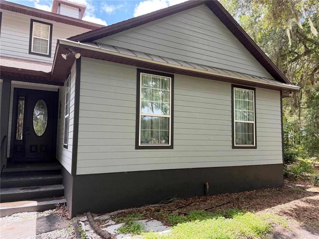 A gray-sided house exterior features a dark front door, two windows, and a metal roof — 18900 LAKEVIEW DRIVE, CLERMONT, FL