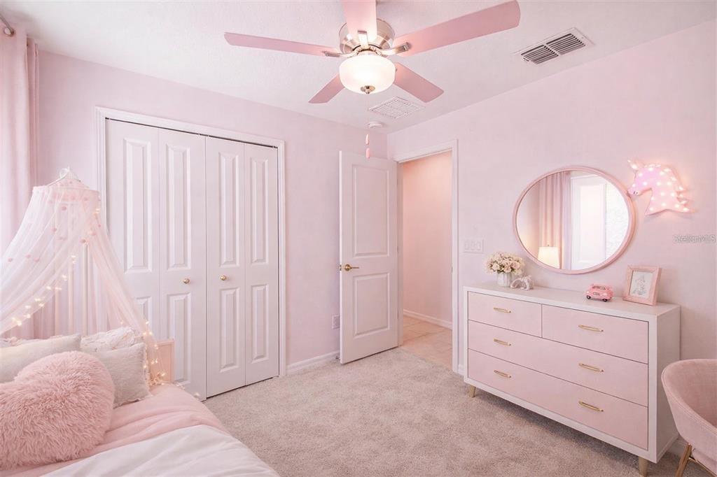 A pink-themed bedroom features a white dresser, a circular mirror, and a canopy bed — 9828 BRANCHING SHIP TRACE, WESLEY CHAPEL, FL