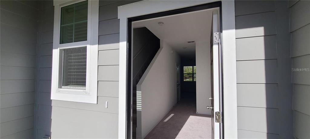 An open front door reveals a carpeted entryway with a staircase and a distant window — 393 MADISON DRIVE, DAVENPORT, FL