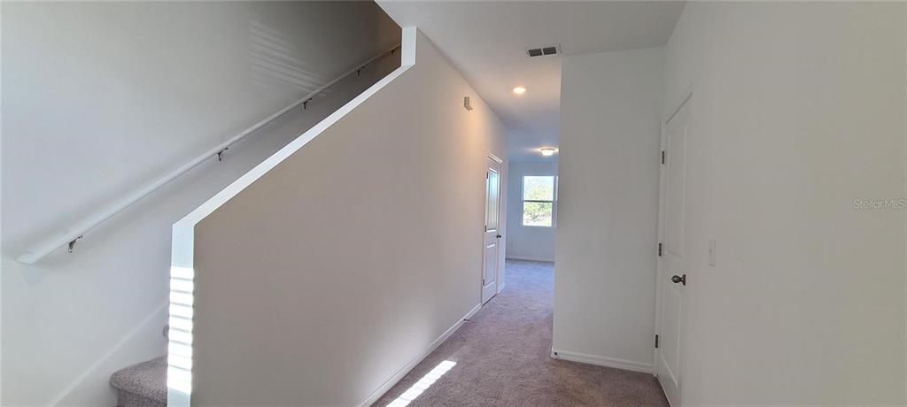 A carpeted hallway features a staircase on the left and two closed interior doors — 393 MADISON DRIVE, DAVENPORT, FL