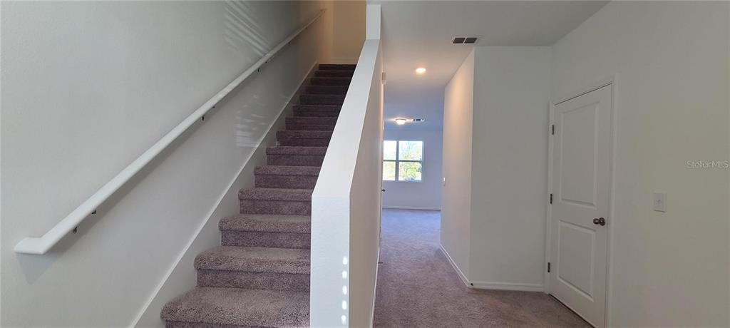 A carpeted staircase leads upward next to a hallway with a closed door — 393 MADISON DRIVE, DAVENPORT, FL