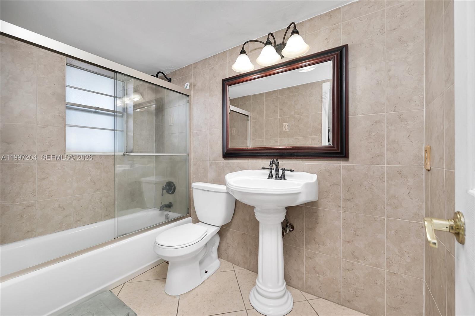 A bathroom features a pedestal sink, a toilet, and a shower-tub combo with tiled walls — 7620 Carlyle Ave # 204, Miami Beach FL 33141, MIAMI BEACH, FL