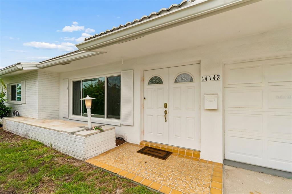 The exterior of a white house features a double front door and a tiled porch — 14142 90TH AVENUE, SEMINOLE, FL