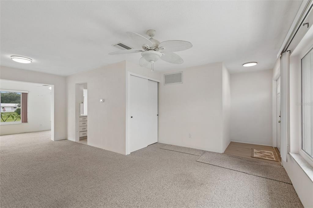 A carpeted living room features a ceiling fan, a white closet, and an entryway door — 14142 90TH AVENUE, SEMINOLE, FL