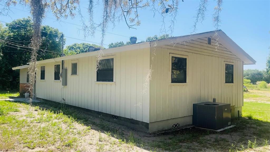The exterior of a light-colored, single-story house with vertical siding and an outdoor AC unit — 703 GOTTS ROAD, DAVENPORT, FL