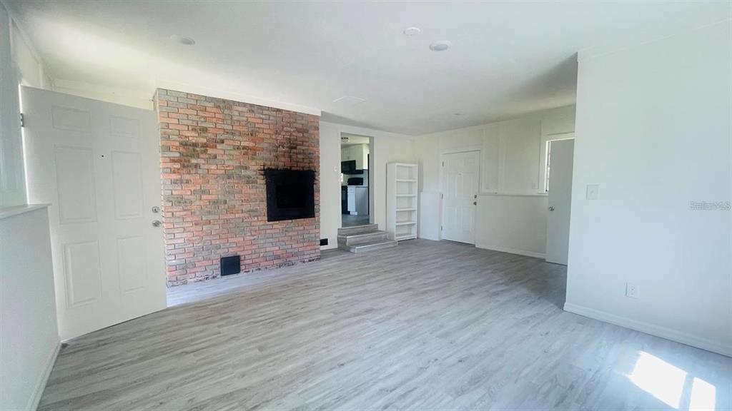 A living room features light wood-look flooring, a brick fireplace, and white walls — 703 GOTTS ROAD, DAVENPORT, FL