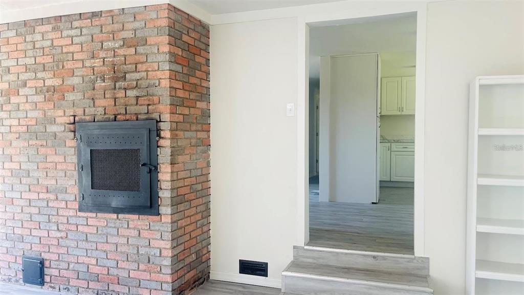 A brick fireplace with a black insert sits next to a doorway leading to a kitchen — 703 GOTTS ROAD, DAVENPORT, FL