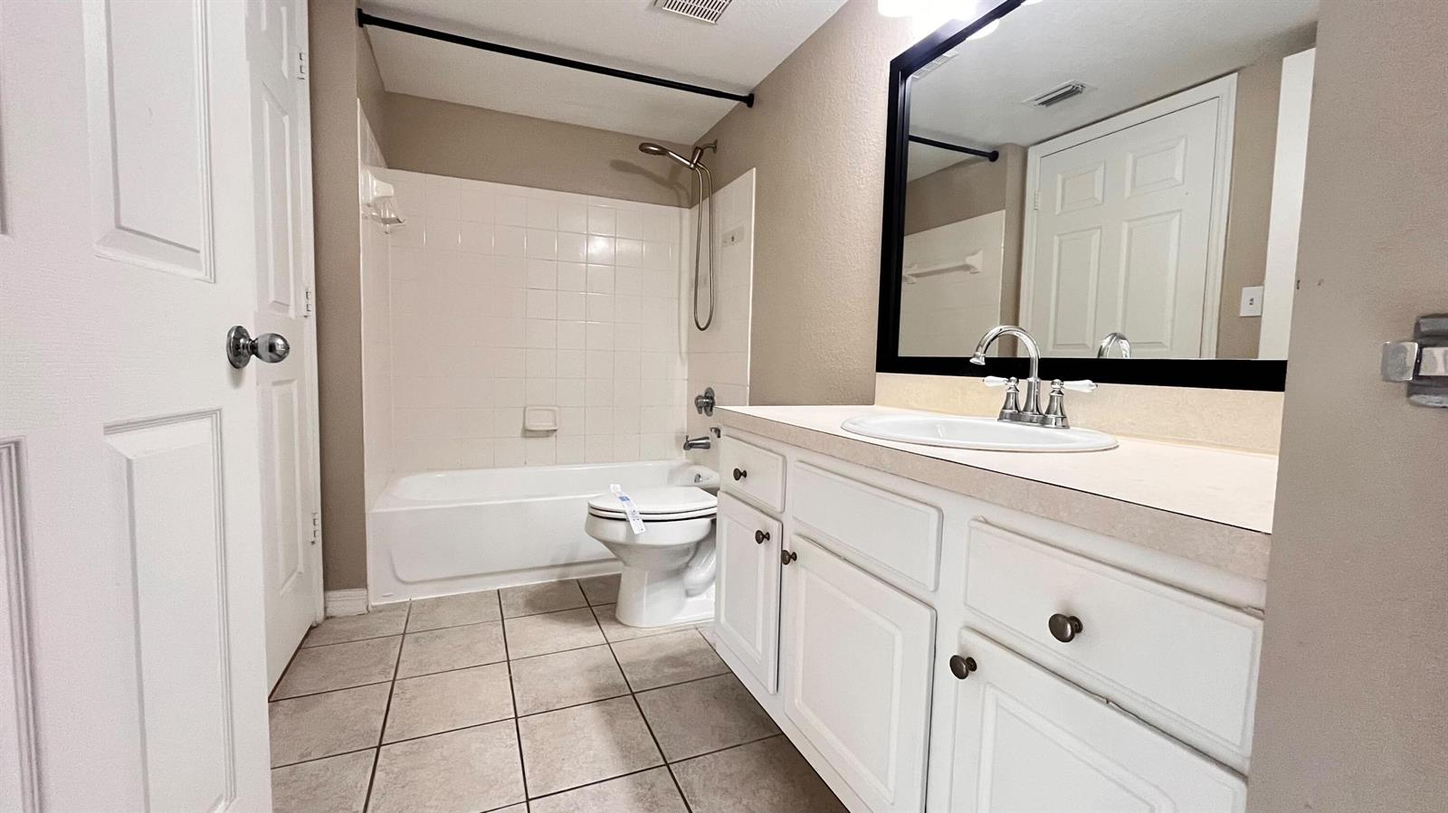 A bathroom features a white vanity, a tiled tub-shower combination, and a black-framed mirror — 15035 Michelangelo 202 Boulevard # 202, Delray Beach FL 33446, DELRAY BEACH, FL