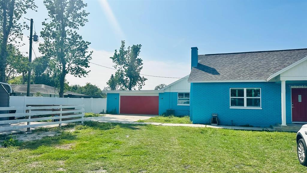 A bright blue brick house features a red garage door and a matching red front door — 6804 BARRY ROAD, TAMPA, FL